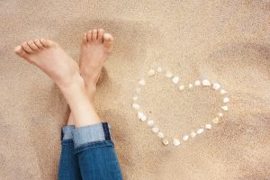 graphicstock female feet closeup of woman standing at the sandy beach next to the shell heart S0OghonZZ