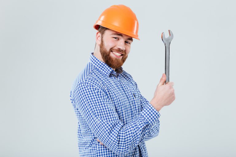 blog 10 Smiling bearded young man in helmet with wrench